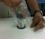 Extract the spool using the top flange while holding the plastic bag down